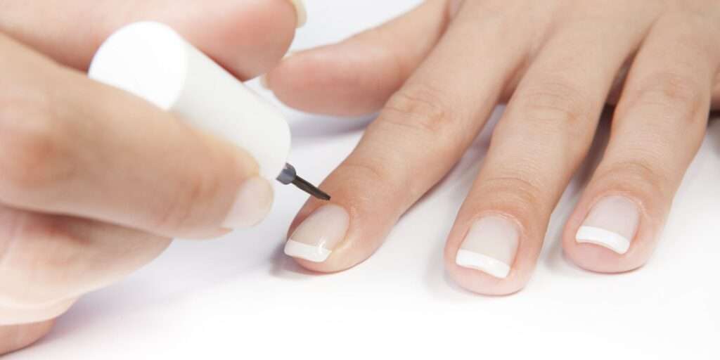 Woman applying a top coat to her French Manicure